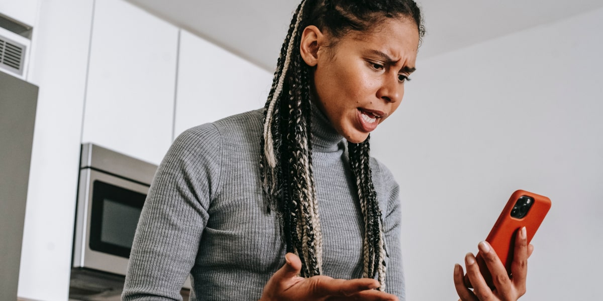 A woman holding a mobile phone, frustrated with the app she's using